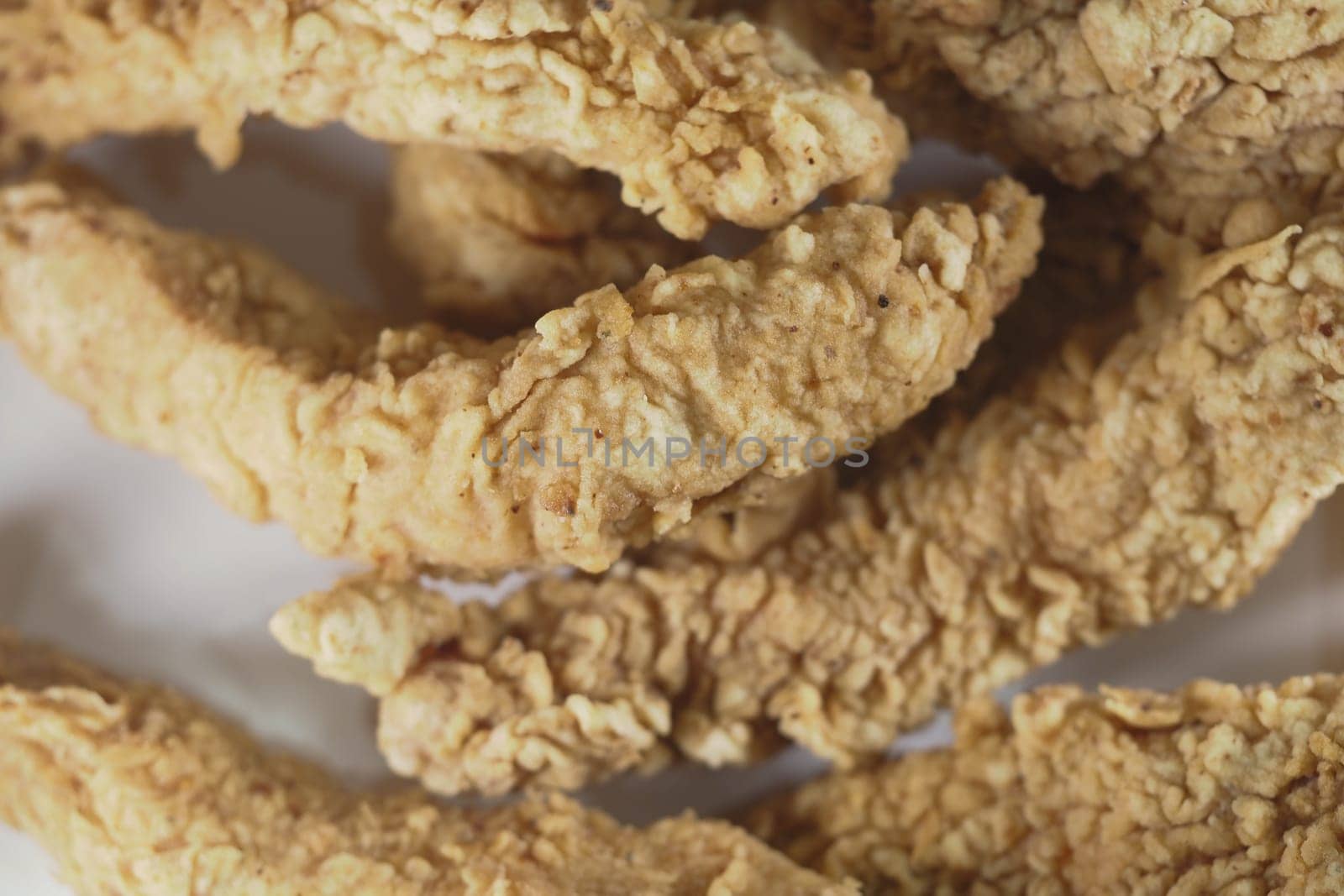 Golden brown, crispy chicken tenders arranged neatly on a plate.
