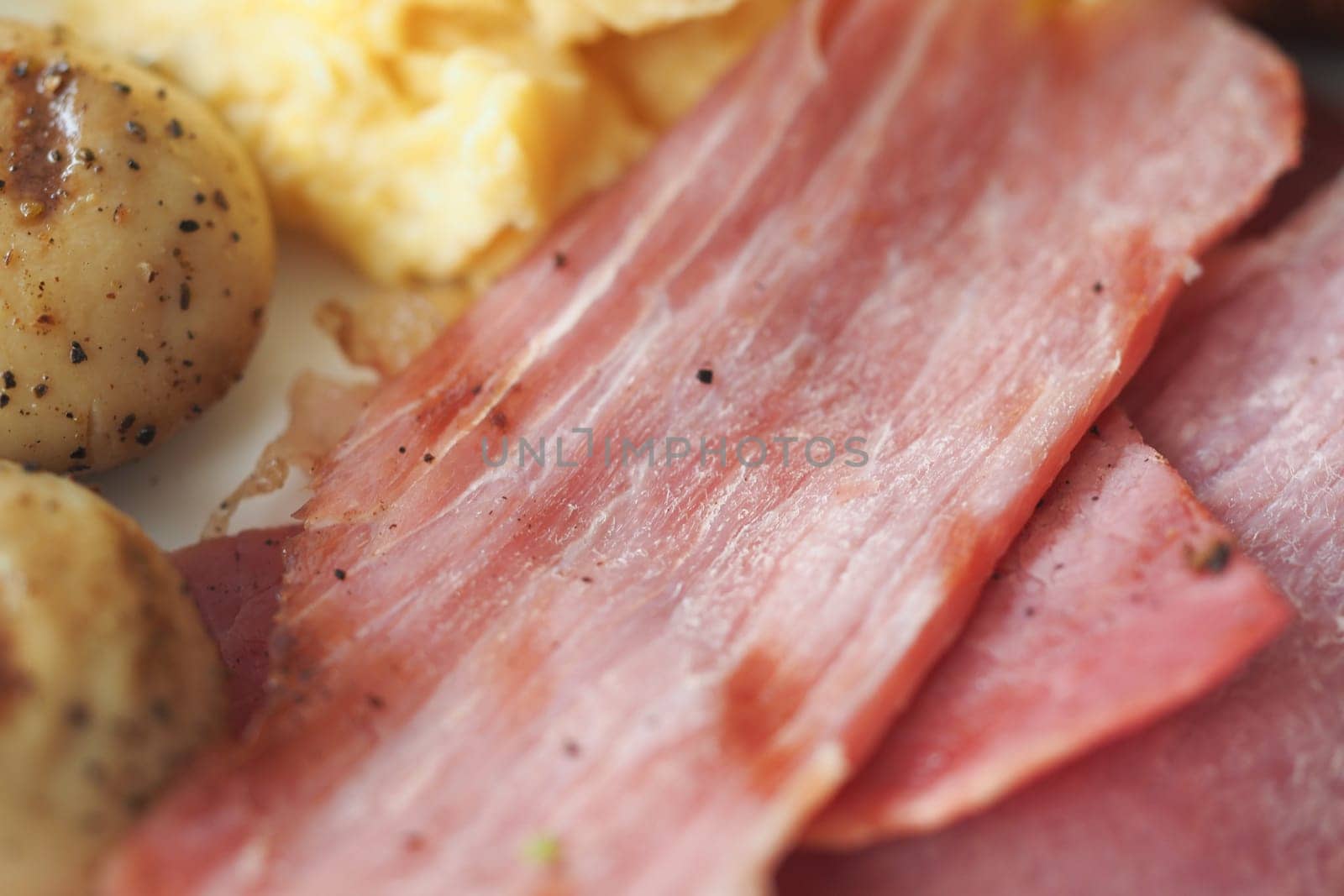 A close-up view of a breakfast platter with eggs and sliced meats.