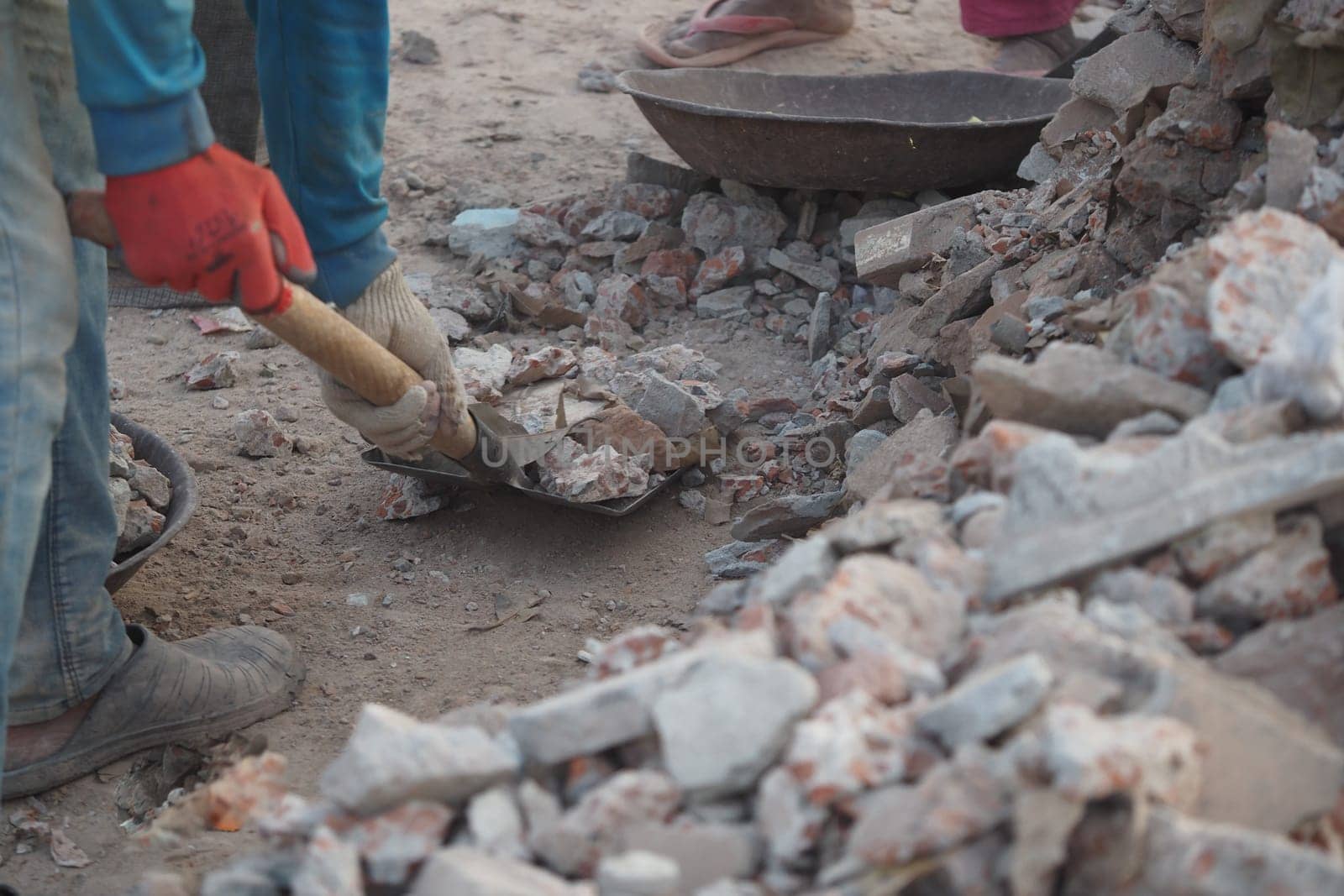 Workers are using tools to remove rubble at a construction site.