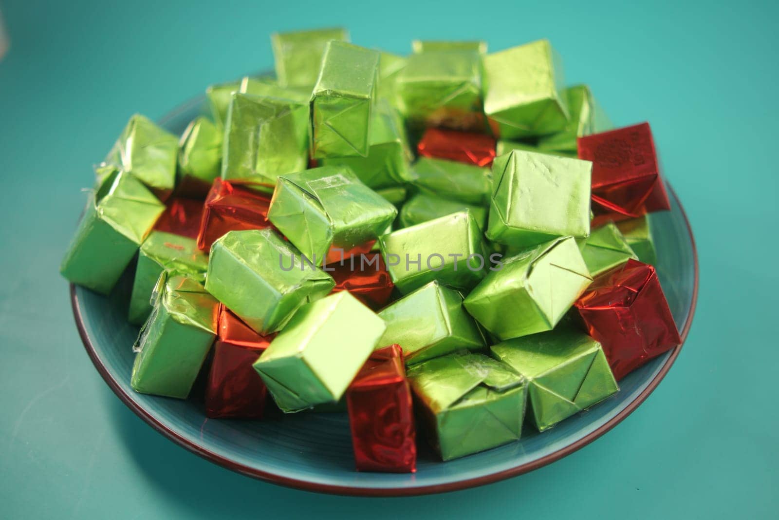 Colorful green and red candies fill a plate, tempting treat lovers.