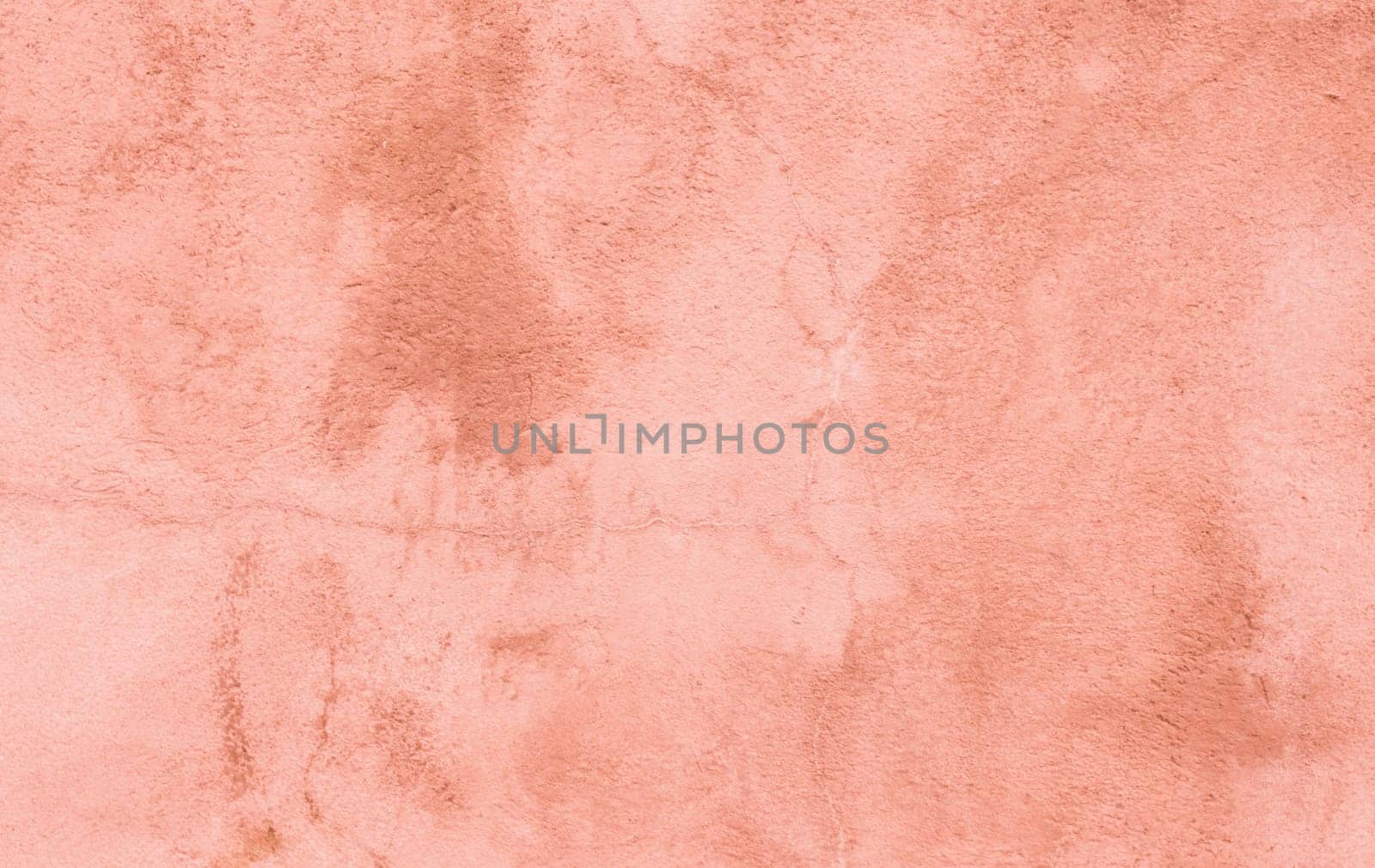 Plastered, weathered and painted pinkish, reddish peach colored concrete wall.