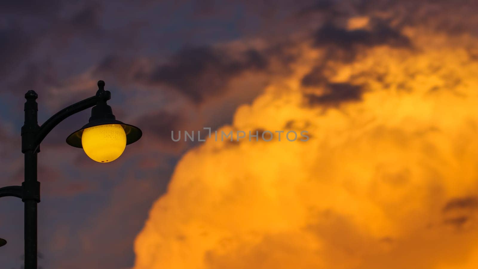 Background of a bright colorful sunset with orange clouds and a yellow street lamp. High quality photo