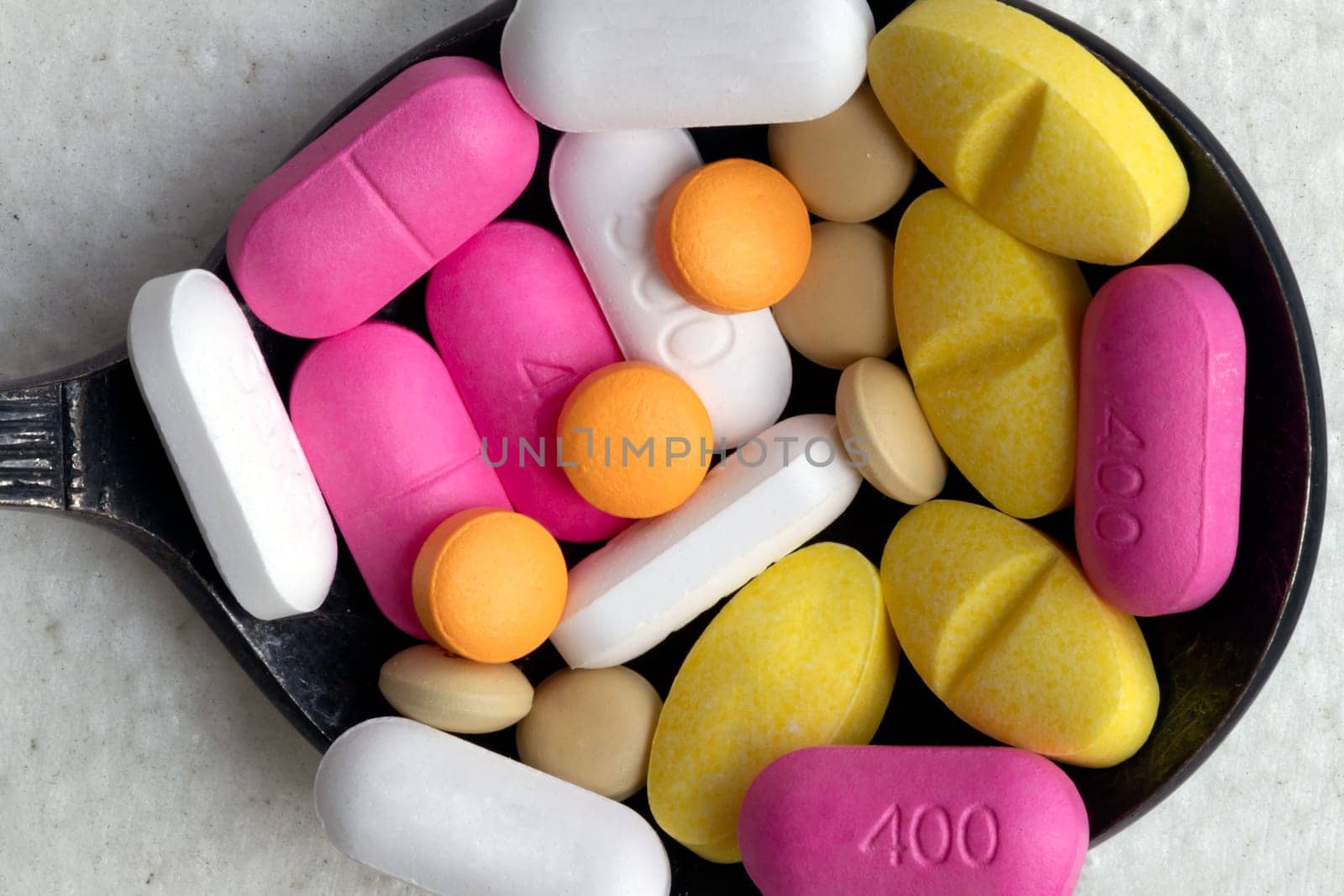 Top down view close up of A lot of pills of different colors and shapes stacked together on metal spoon with white background. Concept of medication treatment and Health care, use it as your Space for text, Design, Wallpaper and Poster, Selective focus.