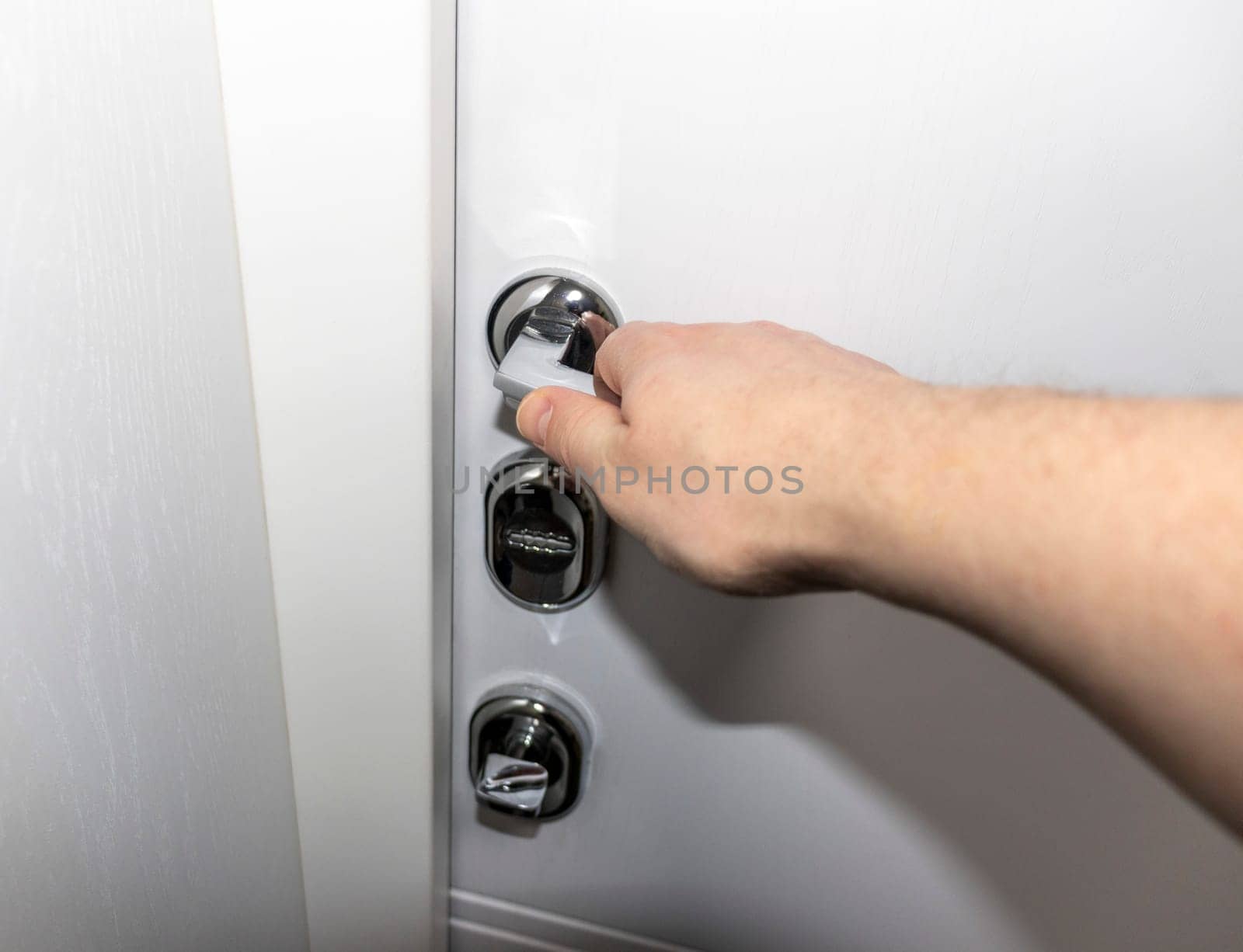 Man opening the door with metal handle and locks.