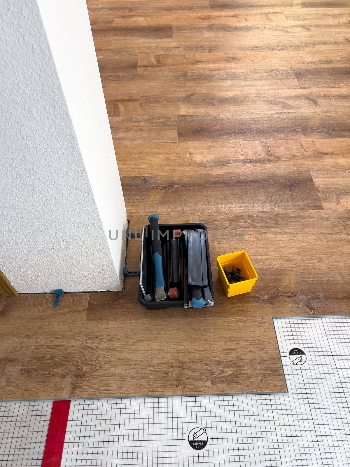 Broomfield, Colorado, USA-February 22, 2025-A close-up view of flooring installation tools placed on a partially completed wood laminate floor. The image shows a toolset, spacers, and an underlayment sheet, highlighting the ongoing home renovation process. The setup demonstrates the careful preparation and materials used for a smooth flooring installation.