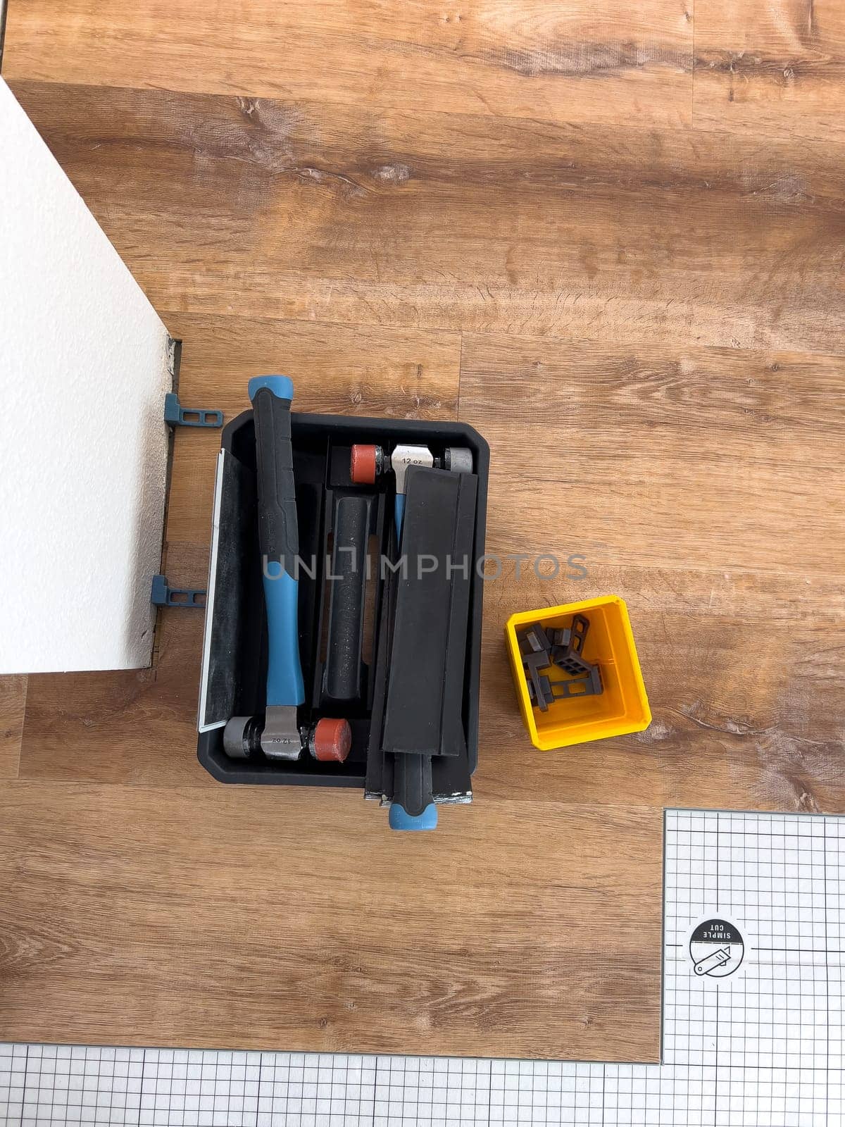 Broomfield, Colorado, USA-February 22, 2025-A close-up view of flooring installation tools placed on a partially completed wood laminate floor. The image shows a toolset, spacers, and an underlayment sheet, highlighting the ongoing home renovation process. The setup demonstrates the careful preparation and materials used for a smooth flooring installation.