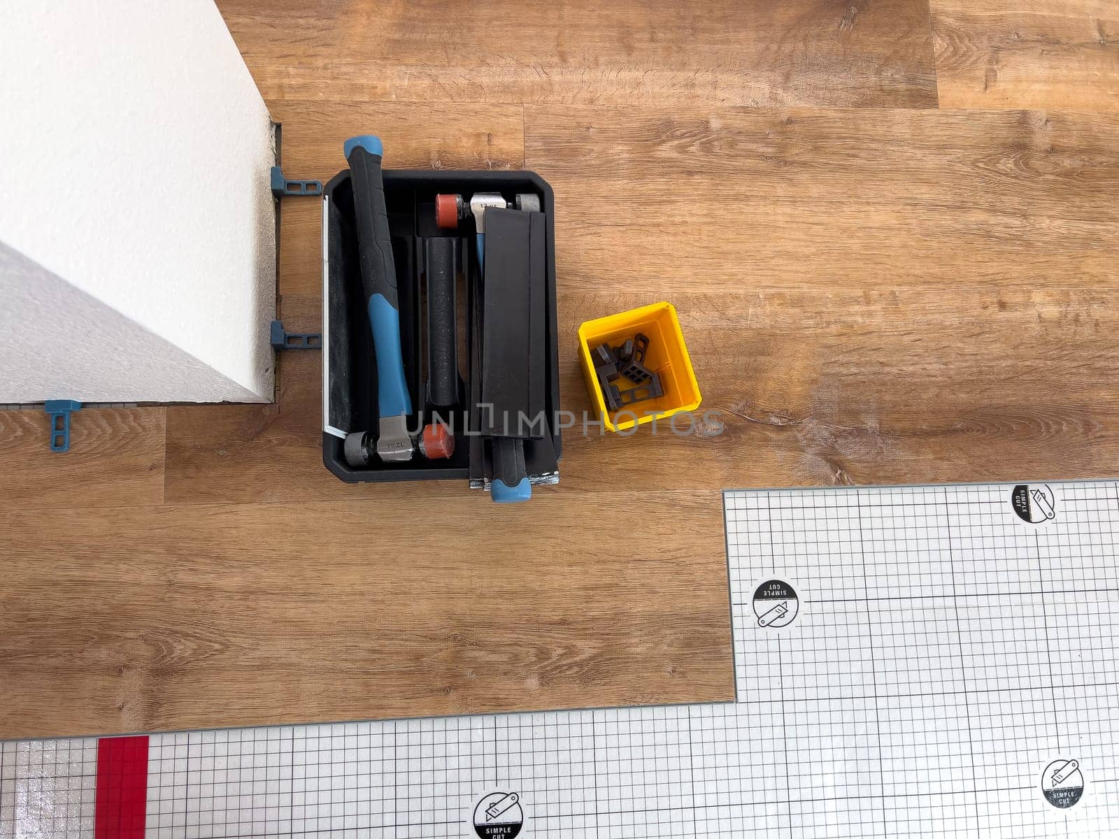 Broomfield, Colorado, USA-February 22, 2025-A close-up view of flooring installation tools placed on a partially completed wood laminate floor. The image shows a toolset, spacers, and an underlayment sheet, highlighting the ongoing home renovation process. The setup demonstrates the careful preparation and materials used for a smooth flooring installation.
