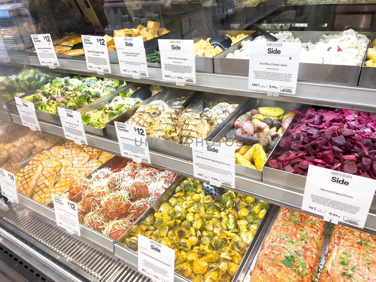 Castle Rock, Colorado, USA-February 22, 2025-A well-stocked Whole Foods deli case displaying a variety of fresh, prepared foods. The selection includes side dishes such as roasted vegetables, pasta salads, coleslaw, and other gourmet deli offerings. Each tray is labeled with pricing and descriptions, providing convenient meal options for customers.