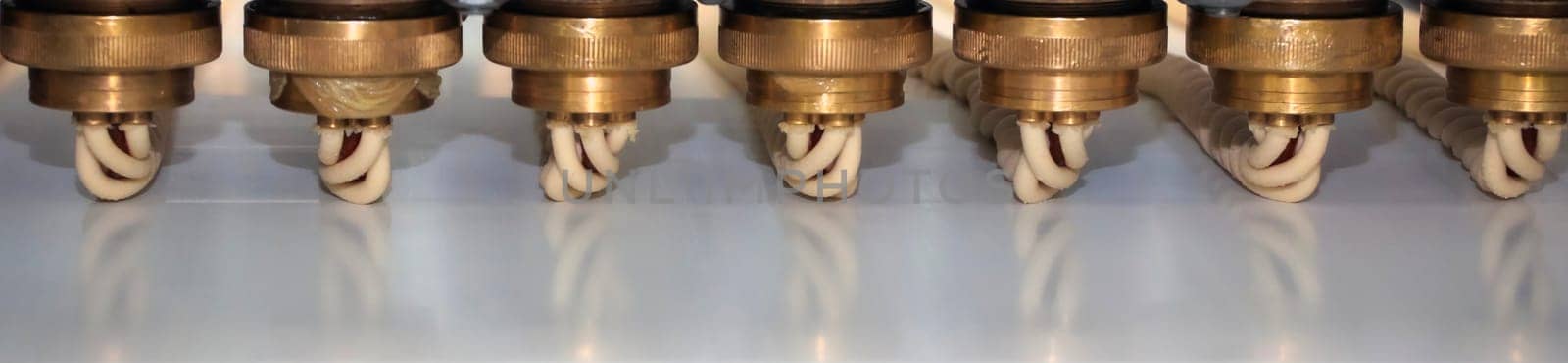 A series of precision nozzles are arranged neatly, connected by tubing, showcasing a component of industrial machinery in a manufacturing facility.
