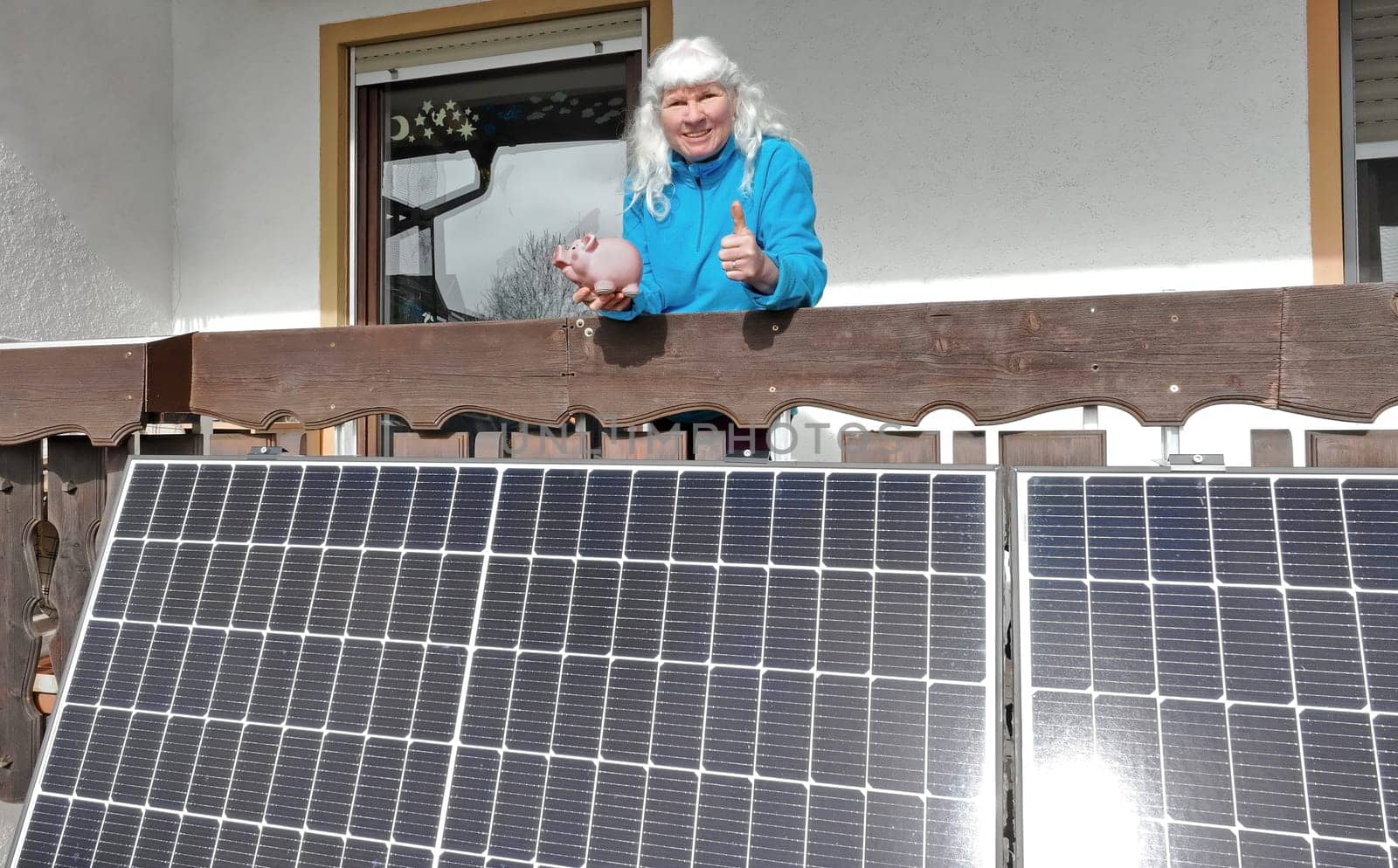 Eine Frau mit einem Sparschwein vor einem Balkonkraftwerk. Geld sparen mit einer kleinen Photovoltaikanlage