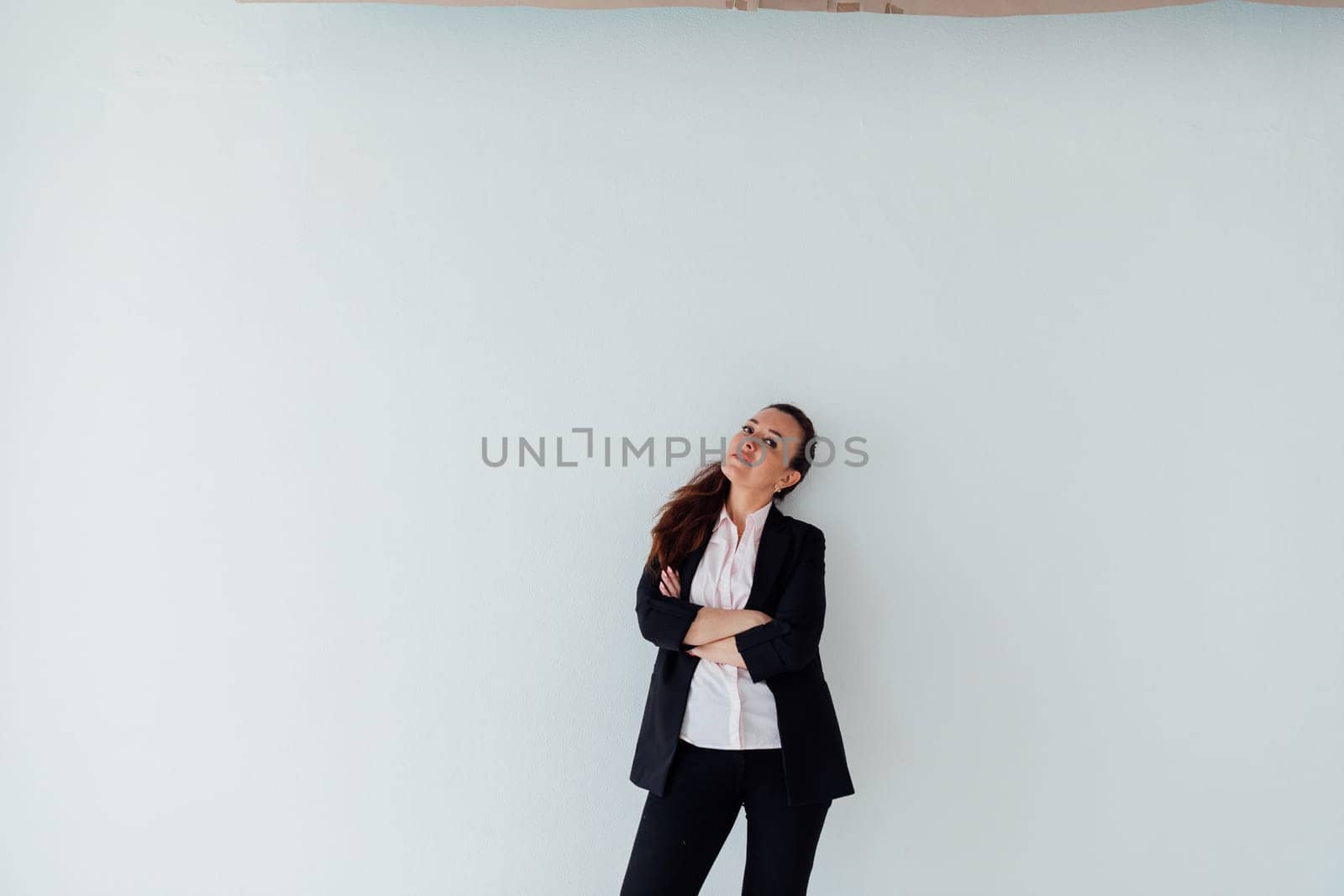 Portrait of a woman of 40 years old in a business suit near a white wall