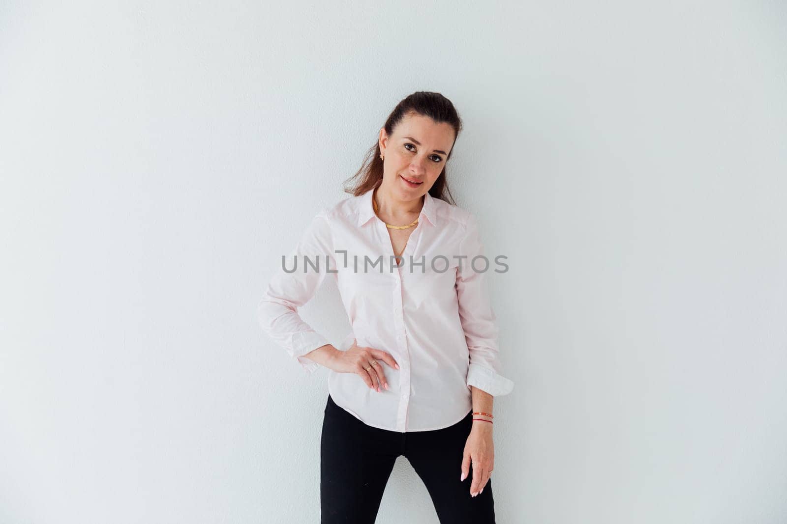 Portrait of a woman of 40 years old in a business suit near a white wall