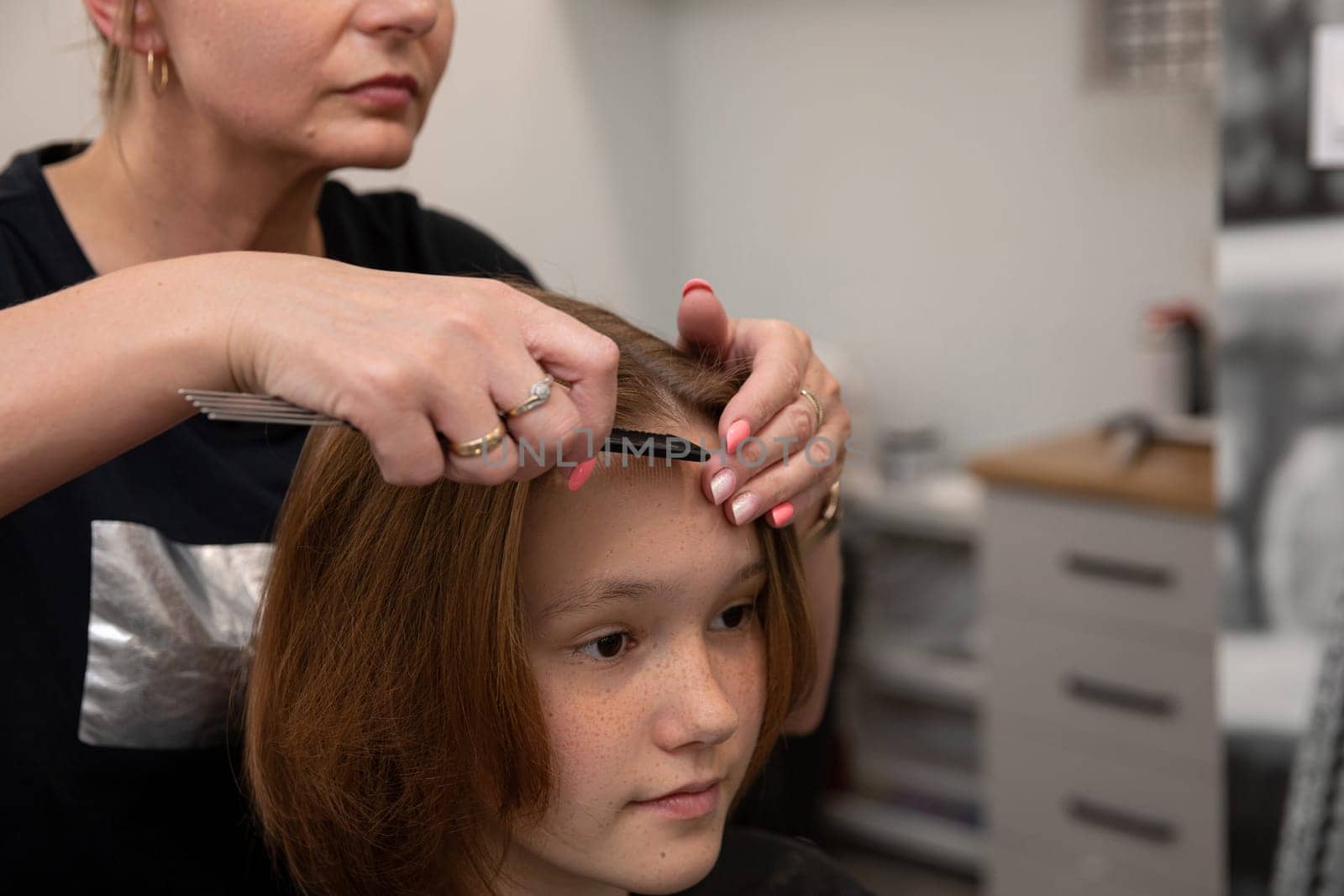 In a contemporary salon atmosphere, a skilled stylist carefully cuts the hair of a young client with expertise
