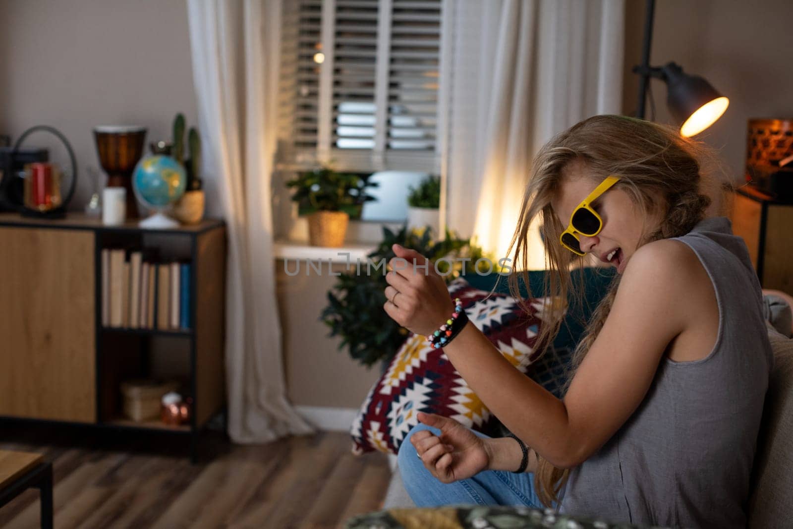 A joyful young woman in stylish sunglasses enjoys her favorite music at home, embracing a warm, inviting vibe
