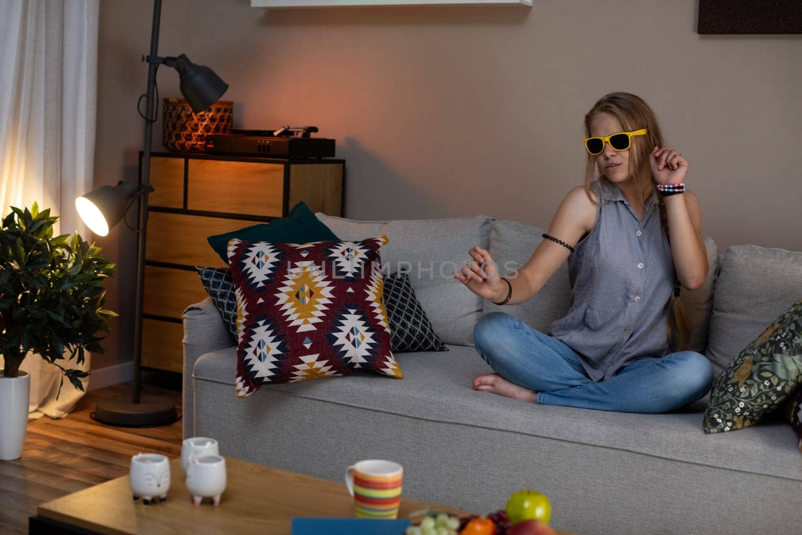 In a relaxed evening scene, a person wearing stylish sunglasses is enjoying their warm and cozy living space