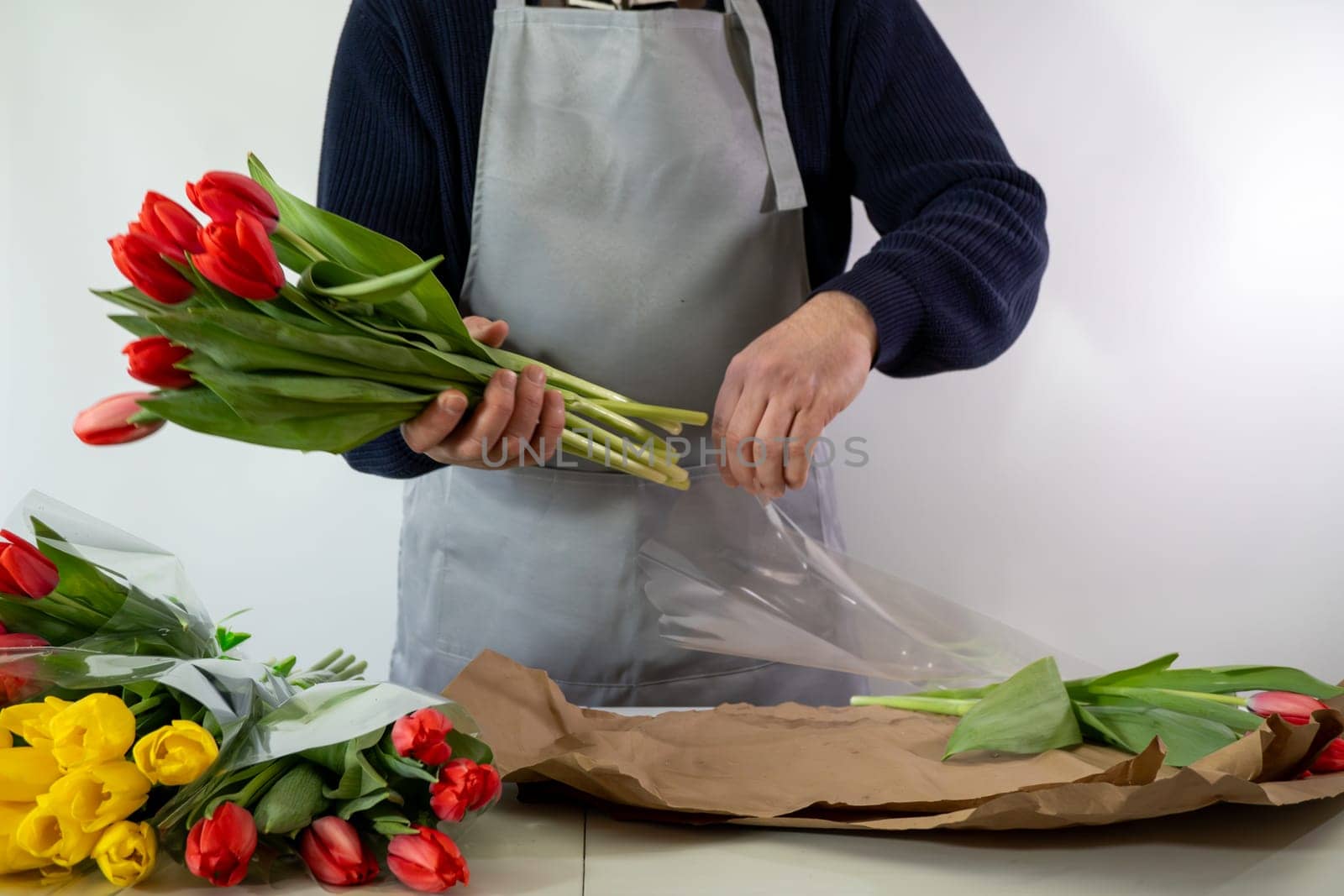 Adult caucasian male florist arranging tulips with care in a flower shop.
