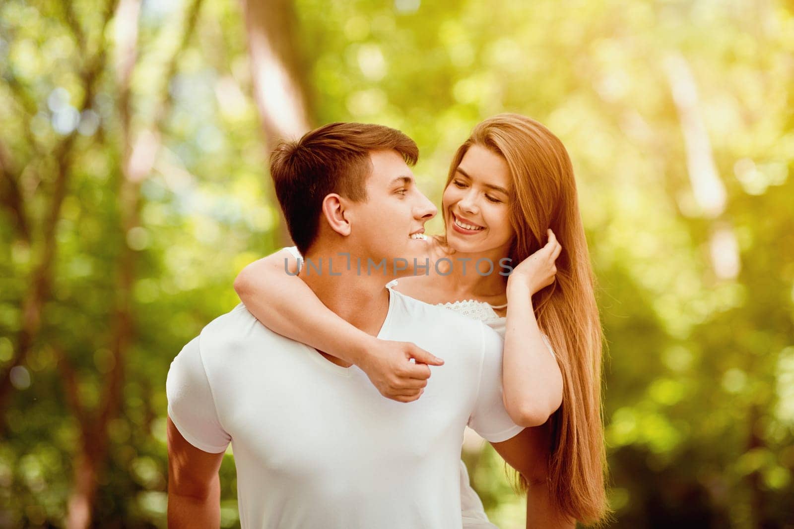 Romantic millennial couple looking at each other lovingly in summer park