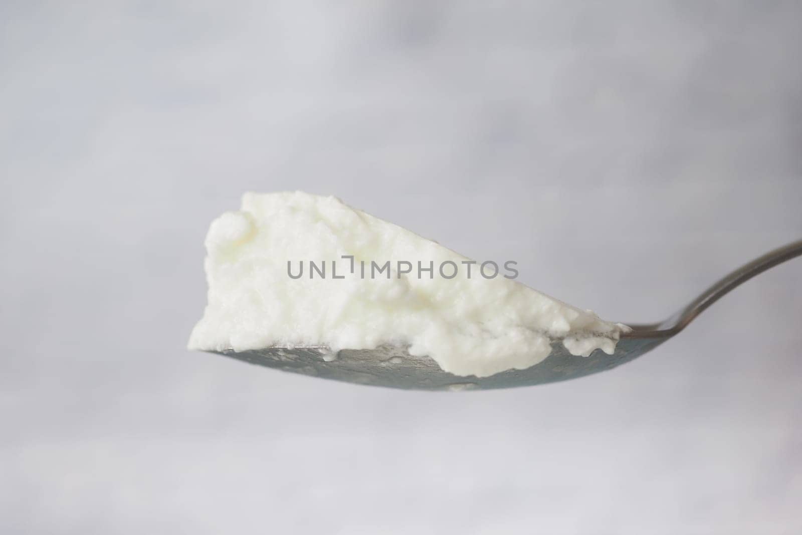 A spoon holds a generous scoop of creamy yogurt with a smooth texture.