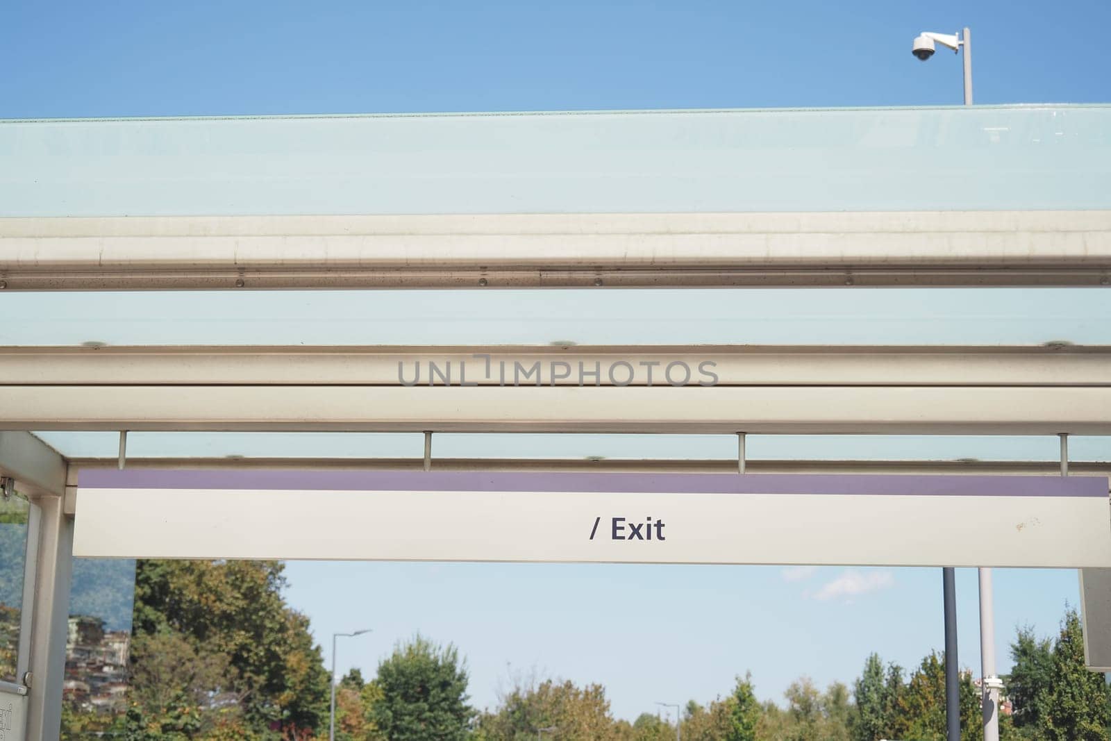 Bright exit sign directs passengers in busy transport area during daytime.