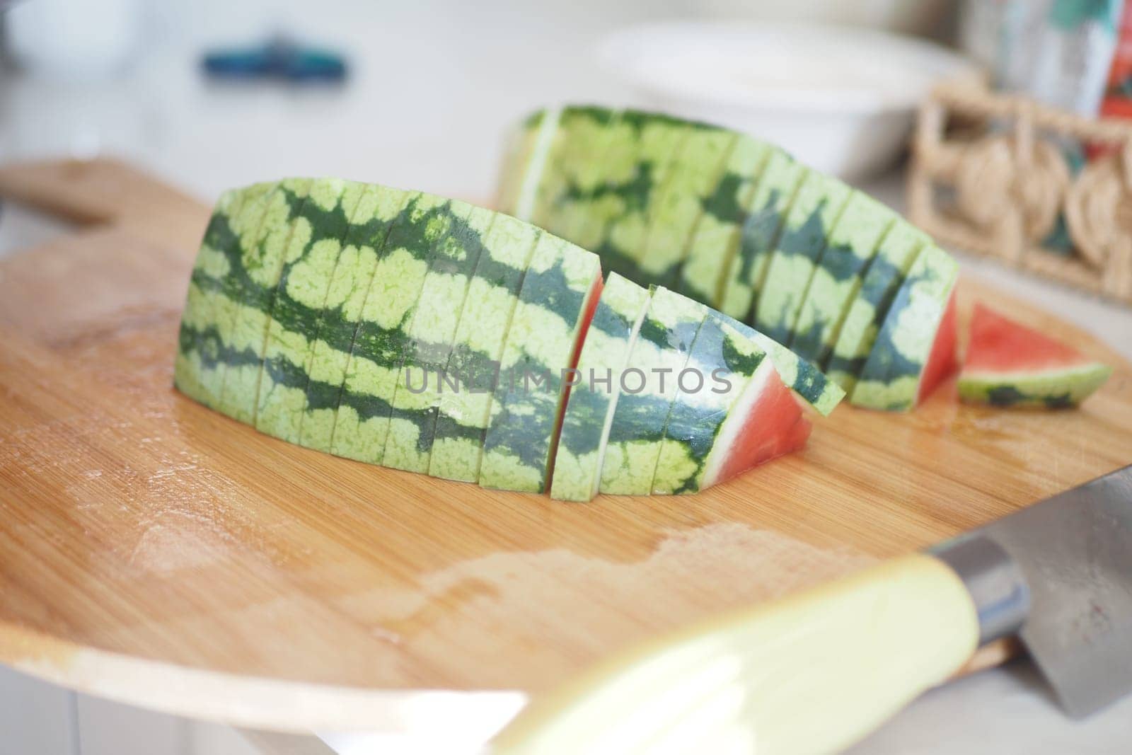 Freshly cut watermelon pieces placed on a wooden cutting board in sunlight.