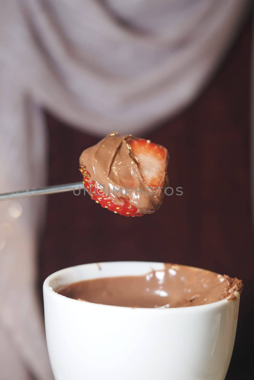 Dipping a fresh strawberry into rich chocolate at a gathering with friends.