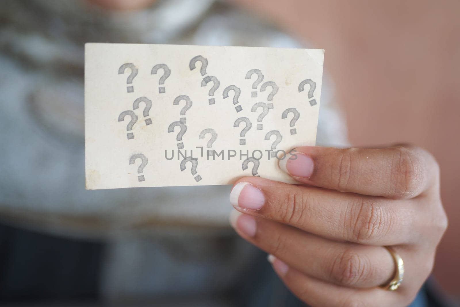 A person considers a card covered in question marks while pondering.