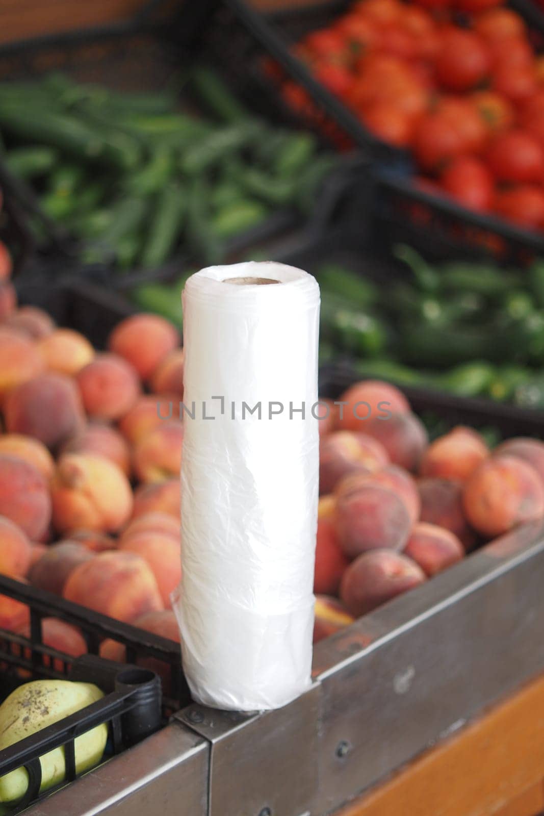 A roll of cleaning paper sits by fresh peaches and veggies at market.
