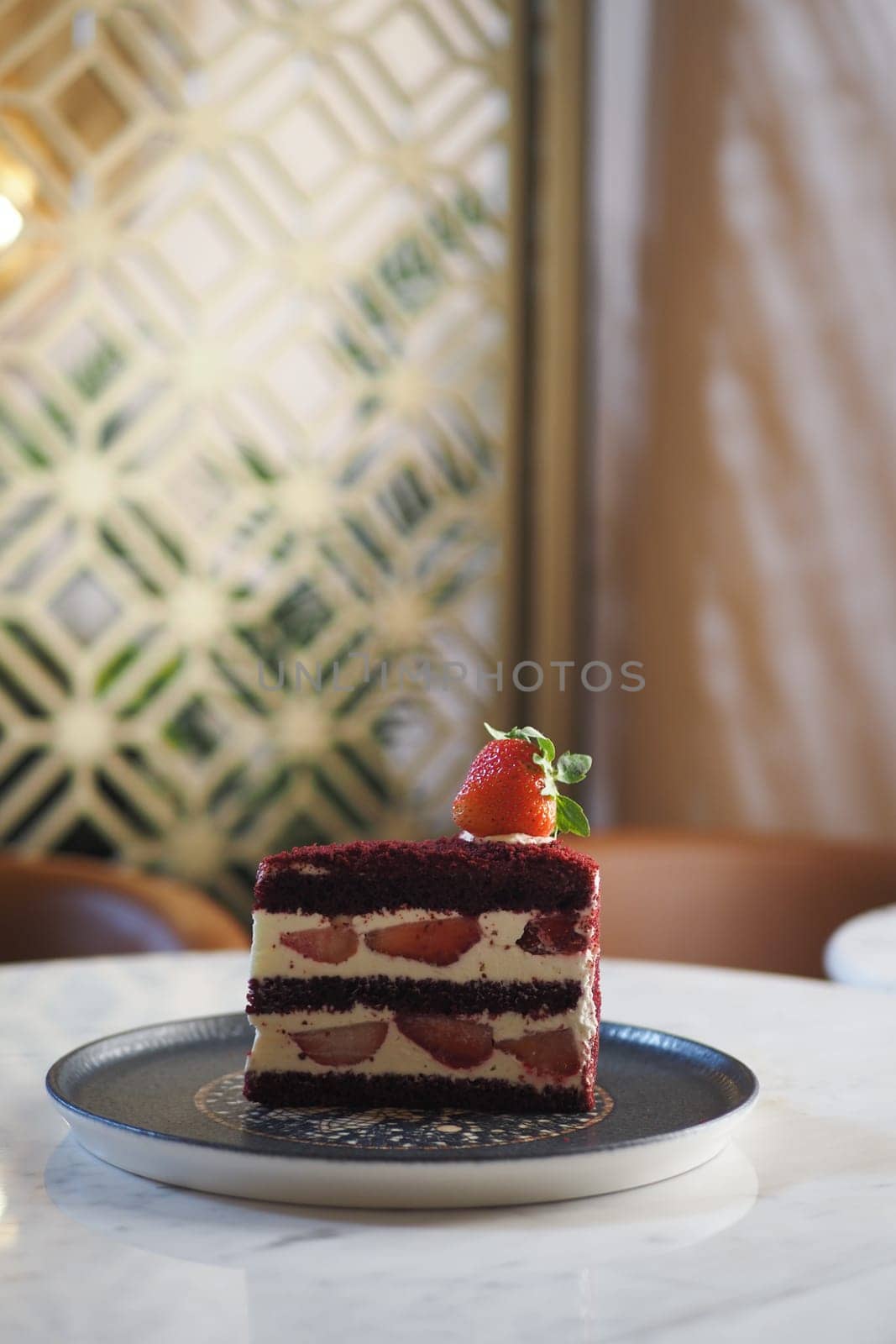 A vibrant red velvet cake topped with fresh strawberries sits elegantly.
