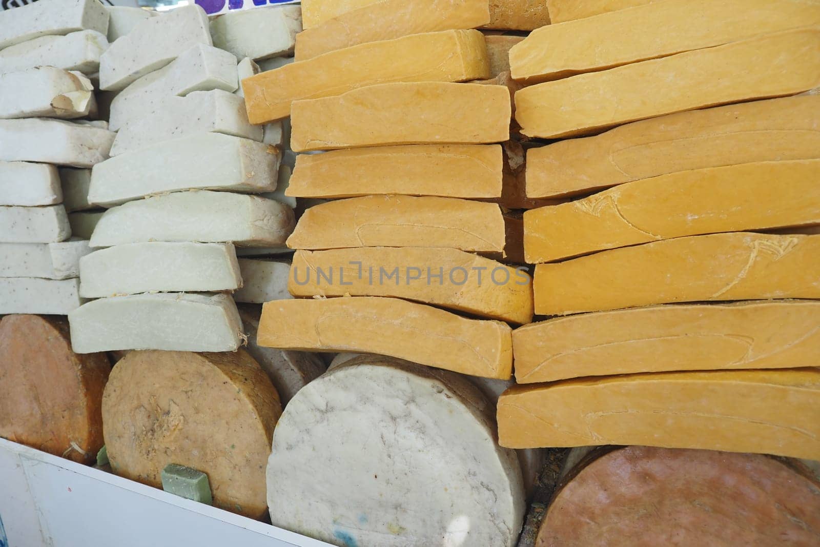 Blocks of different cheese types displayed at a market stall.
