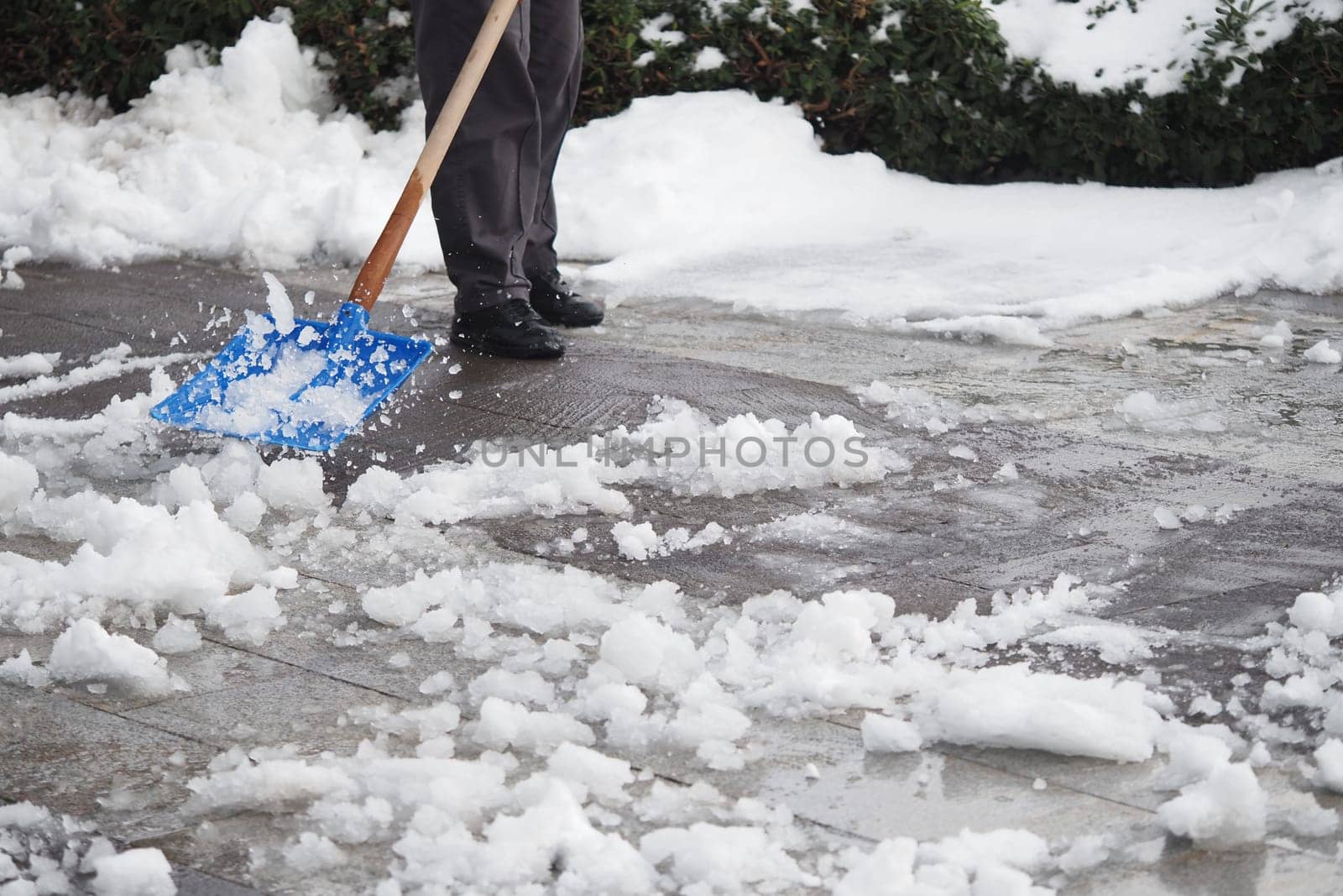 A person clears snow from a walkway using a shovel on a cold day.