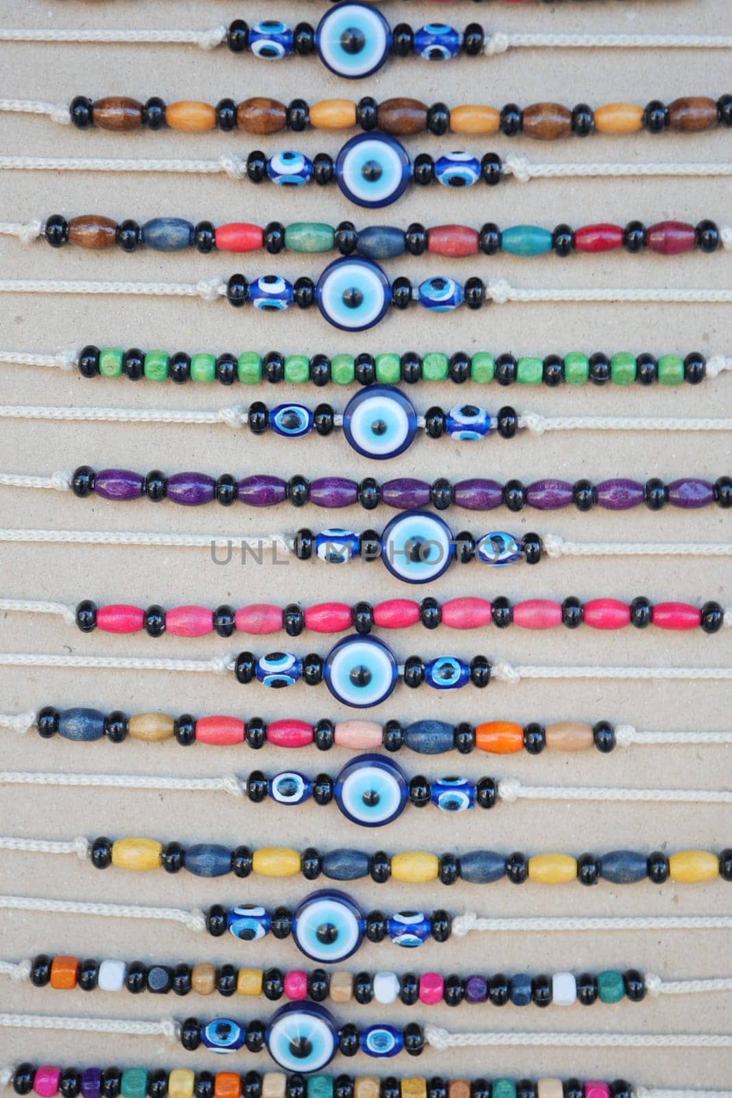 Vibrant necklaces feature various beads arranged in neat rows at a market.