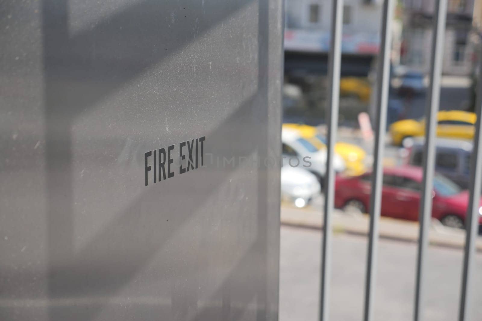 Clear fire exit sign on metal surface near crowded street area