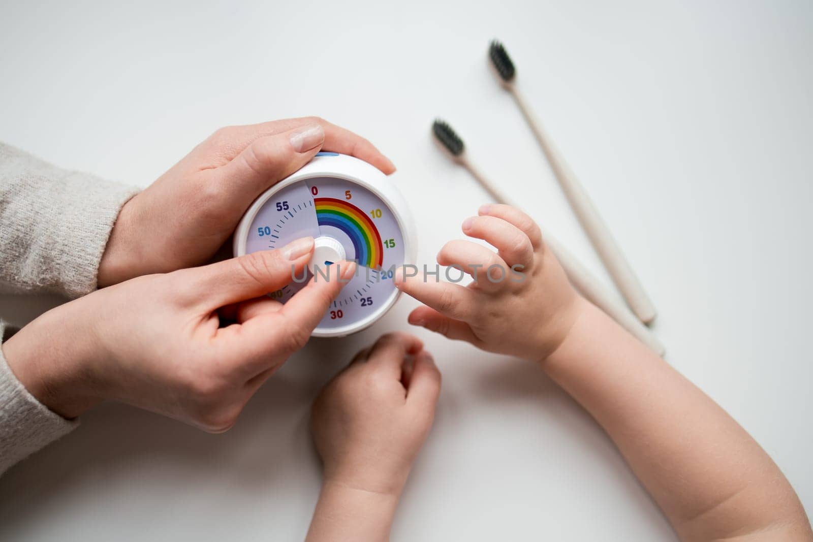 Adult and child using toothbrushing timer with colorful dial for dental hygiene.