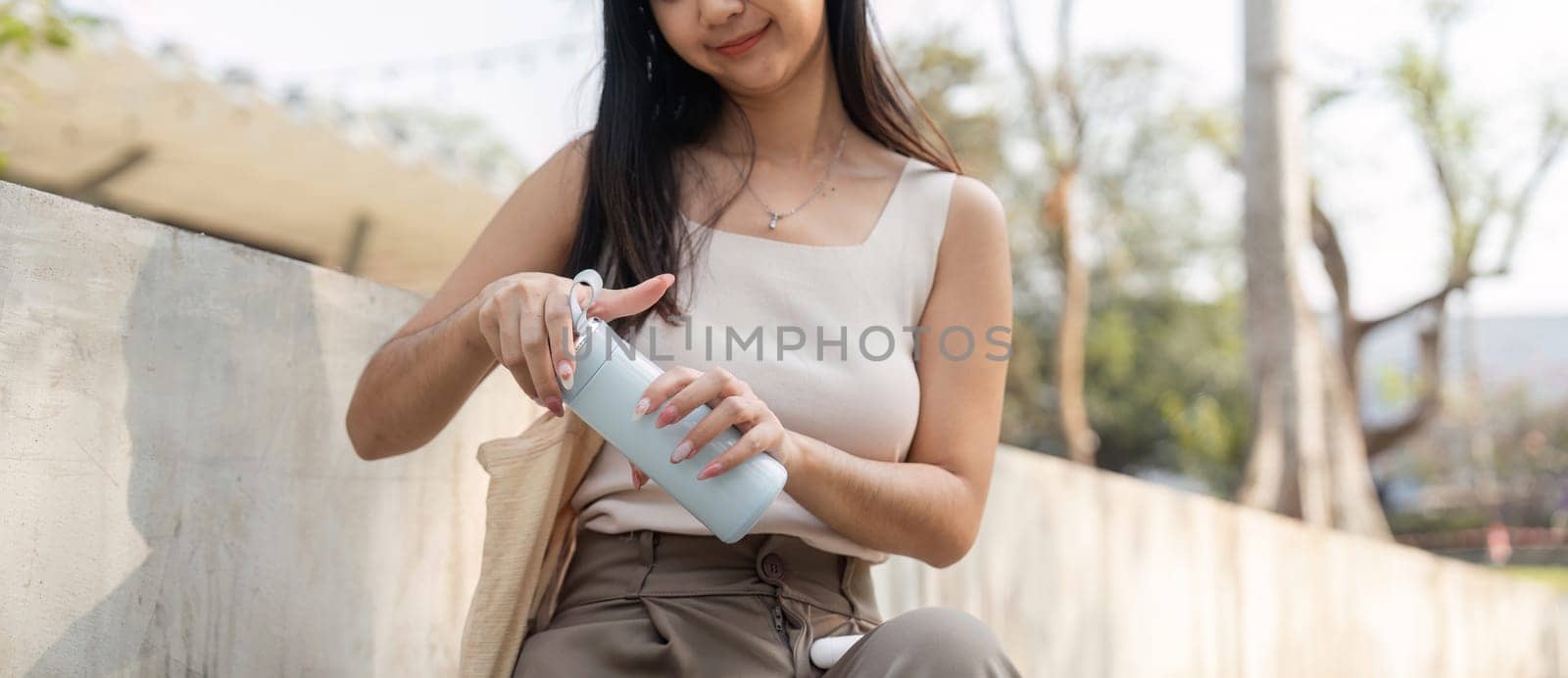 A young woman prepares her reusable cup in a serene outdoor setting, highlighting her commitment to a sustainable lifestyle.