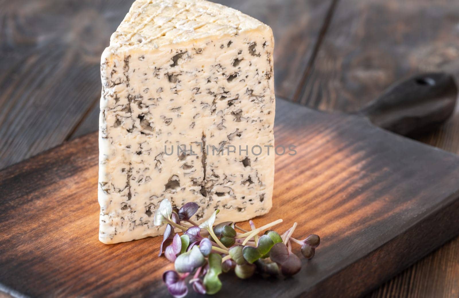 Creamy, veined Roquefort cheese with bold flavor, elegantly placed on a wooden board