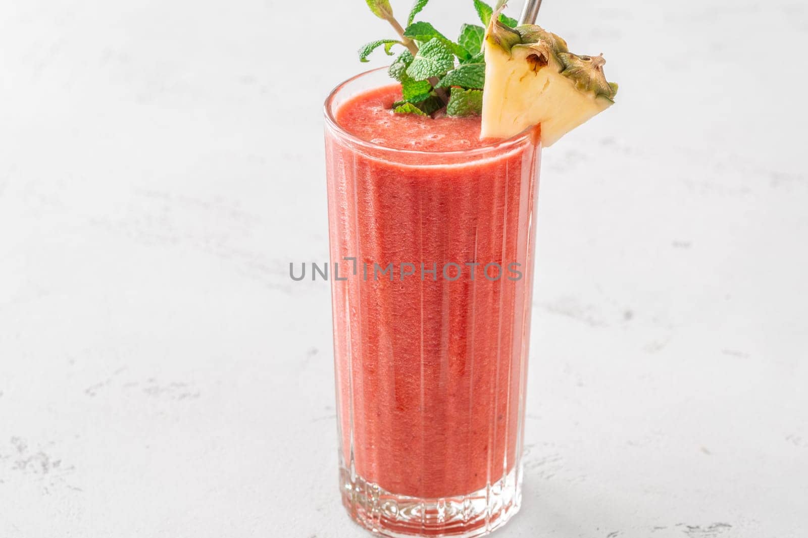 Creamy tropical smoothie with cherry, banana, and pineapple, garnished with mint and pineapple