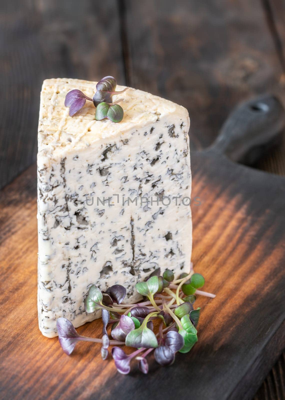 Creamy, veined Roquefort cheese with bold flavor, elegantly placed on a wooden board