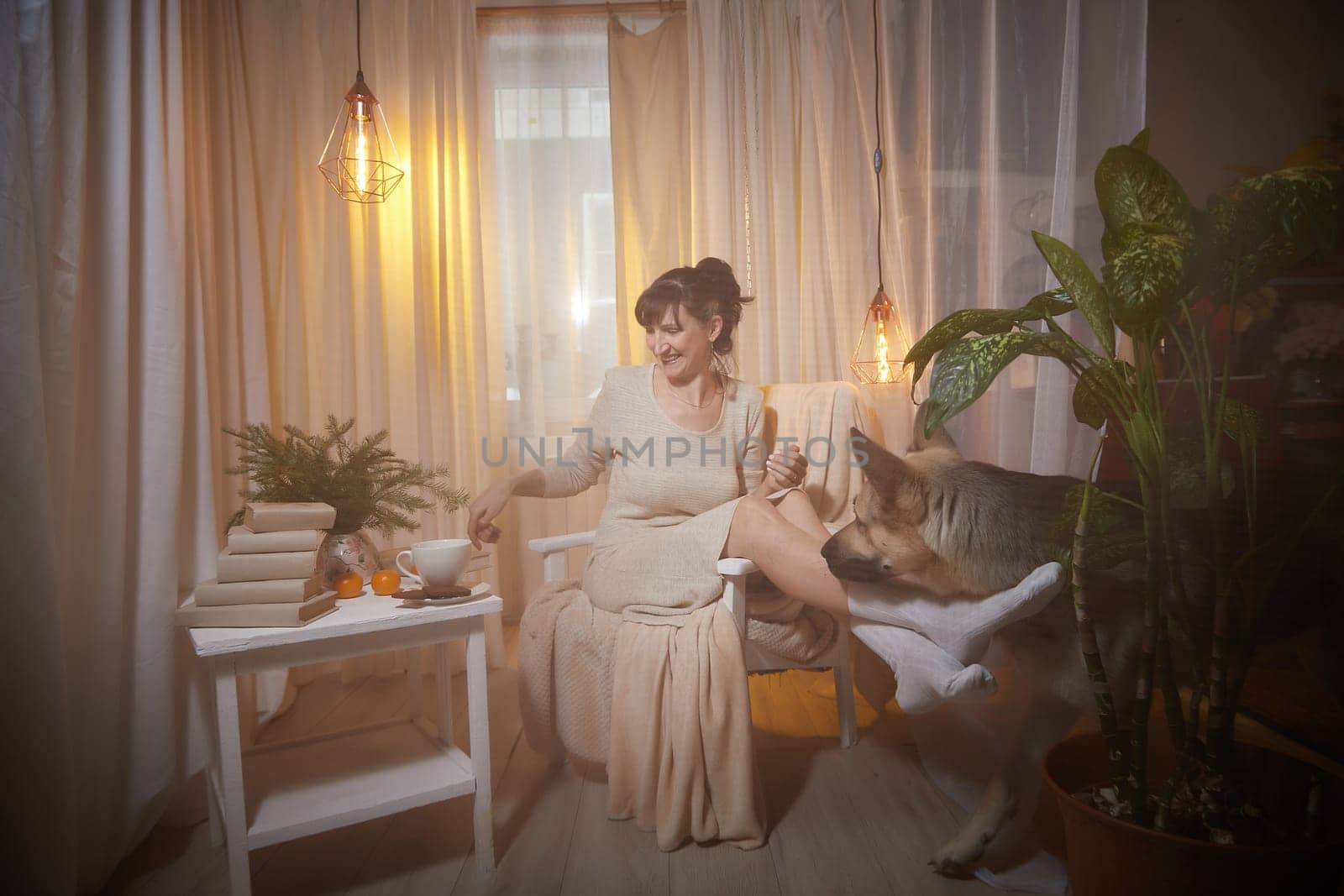 A middle-aged woman sits comfortably in her cozy apartment, savoring the evening atmosphere with a sense of relaxation and pleasure.