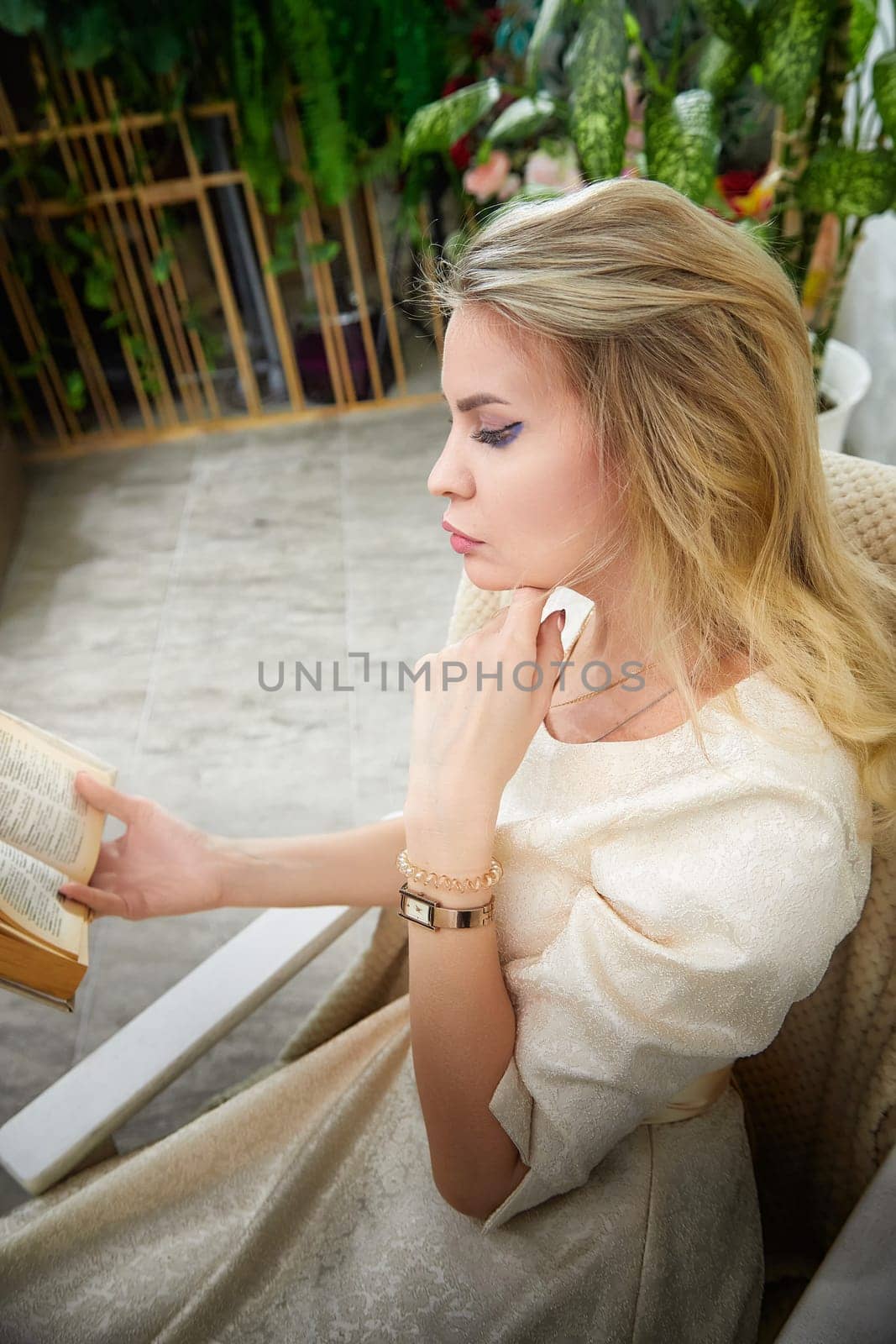 A woman with blonde hair is quietly reading a book, showcasing her lifestyle as a middle-aged blogger in her home.