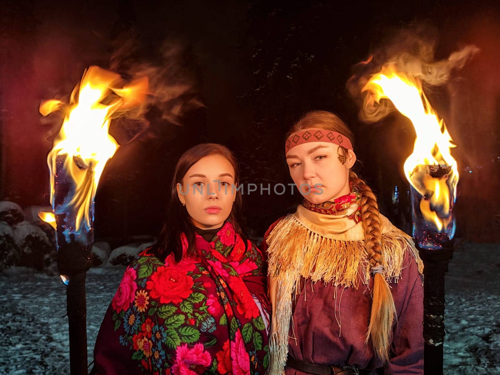 Actors dressed in ethnic costumes showcase a thrilling fire performance amidst a cold winter night, highlighting their bravery and heritage.