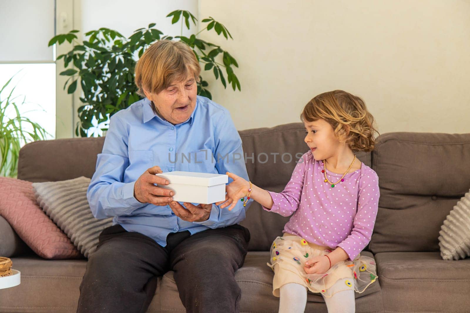 Granddaughter gives her grandmother a gift. Selective focus. Kid.
