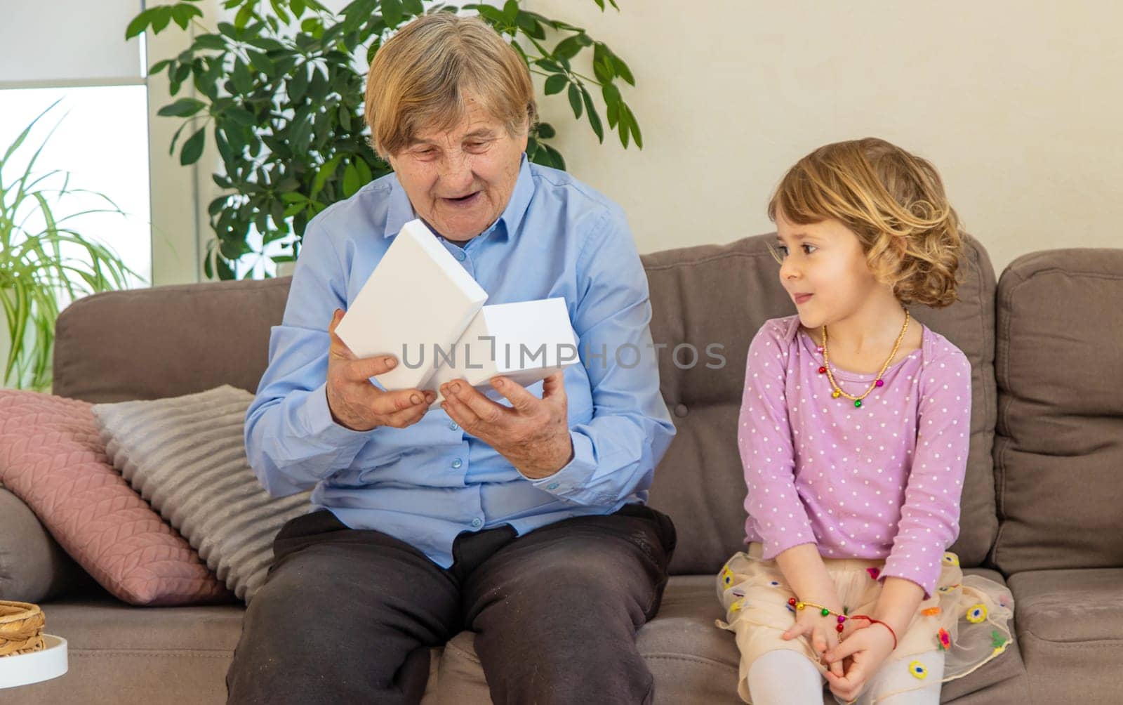 Granddaughter gives her grandmother a gift. Selective focus. Kid.