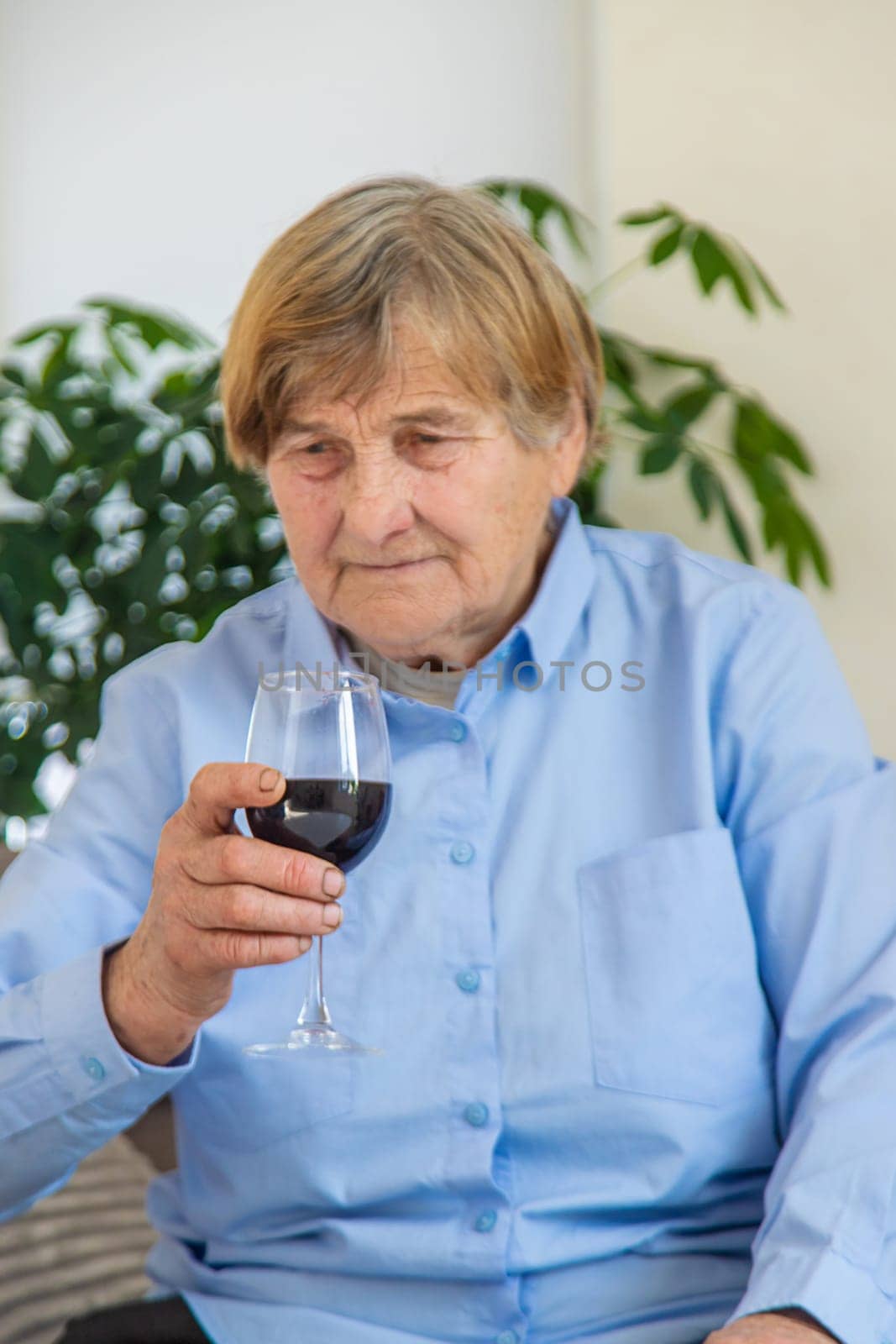 Old woman drinking wine. Selective focus. People,