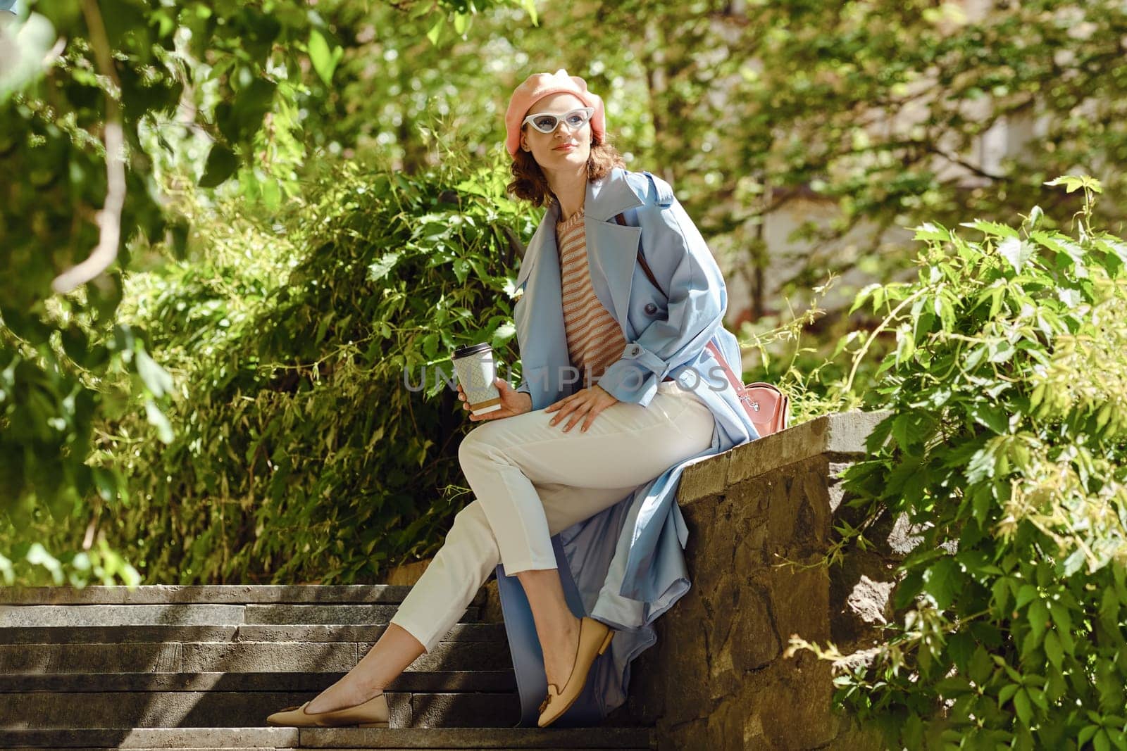 A happy woman sitting among plants, smiling in casual fashionable clothing