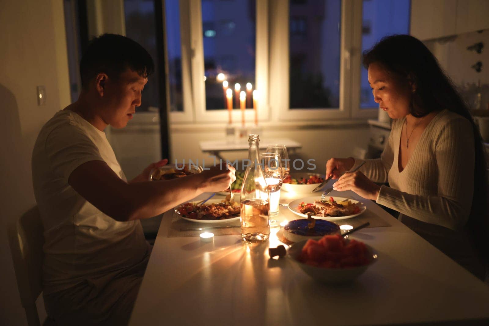 Young asian couple eating dinner by candlelight at their home