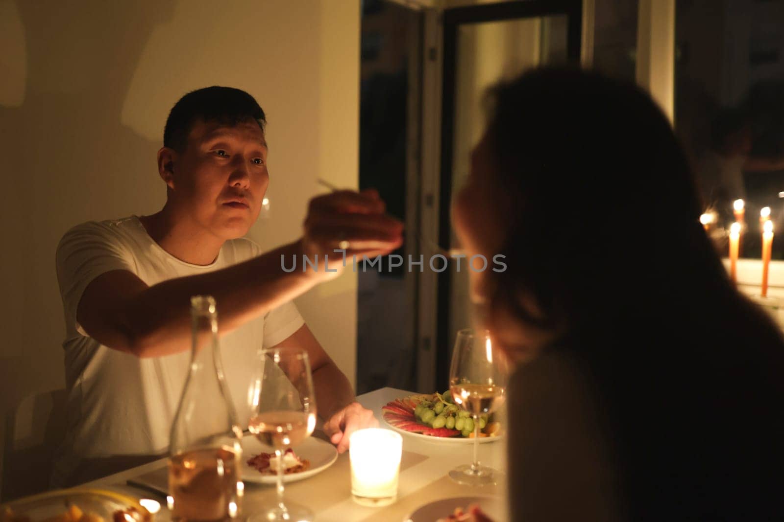 Couple enjoying romantic evening with wine, cheese, and fruit by candlelight