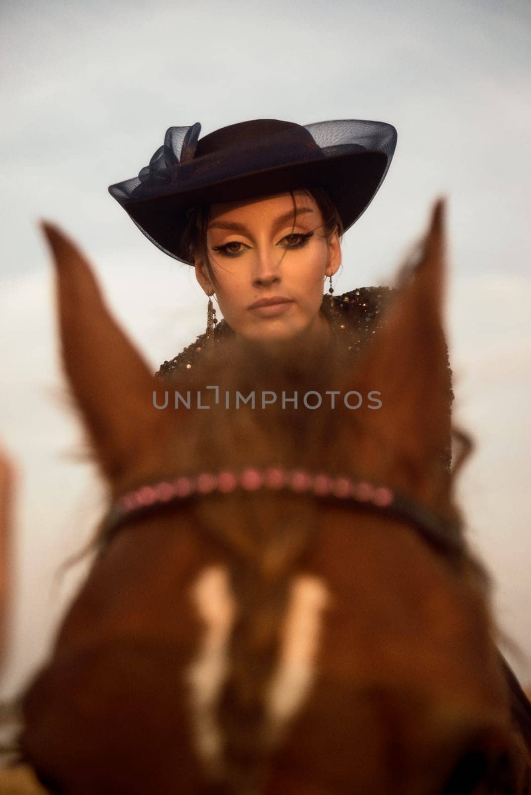 portrait of beautiful equestrian woman who is engaged in horse riding. charming girl in long blue dress. elegant style with gloves and hat. rider is walking in the field. concept of women riding horses