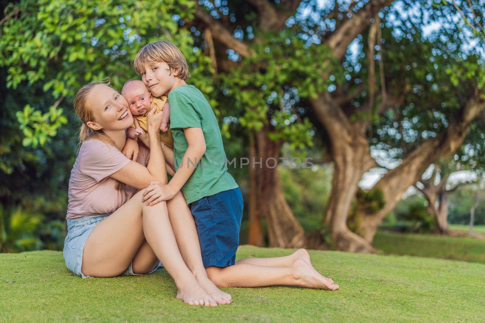 Young mother, teenage son, and one-month-old baby enjoying quality family time in the park. Multigenerational bonding and outdoor family love concept.