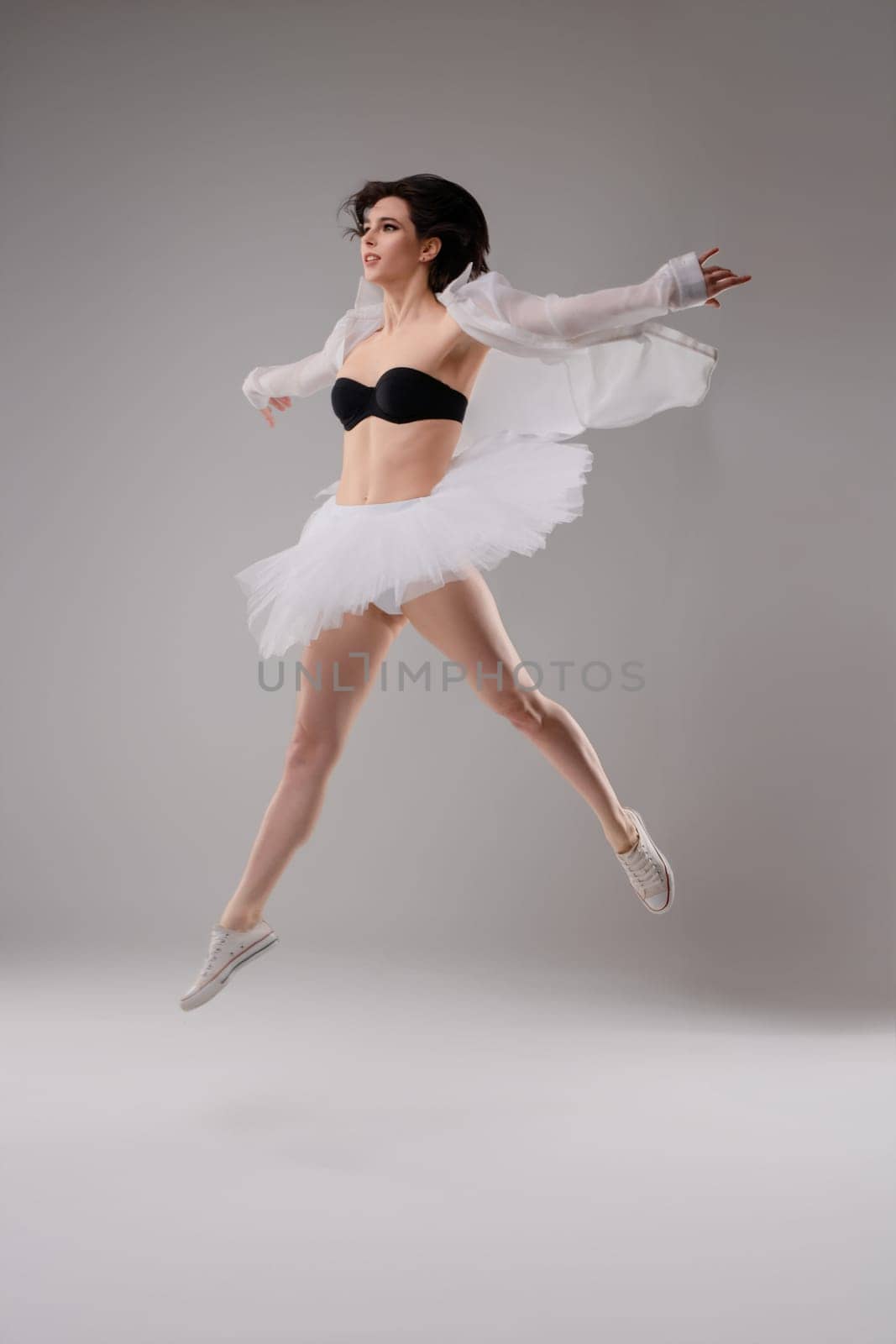 In a dance studio, a woman in lingerie executes a stunning ballet leap, showcasing her grace and strength.