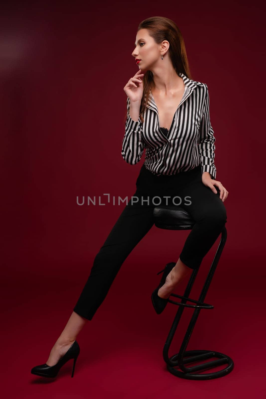 A confident woman showcases her beauty while modeling lingerie in a studio setting with a bold background.